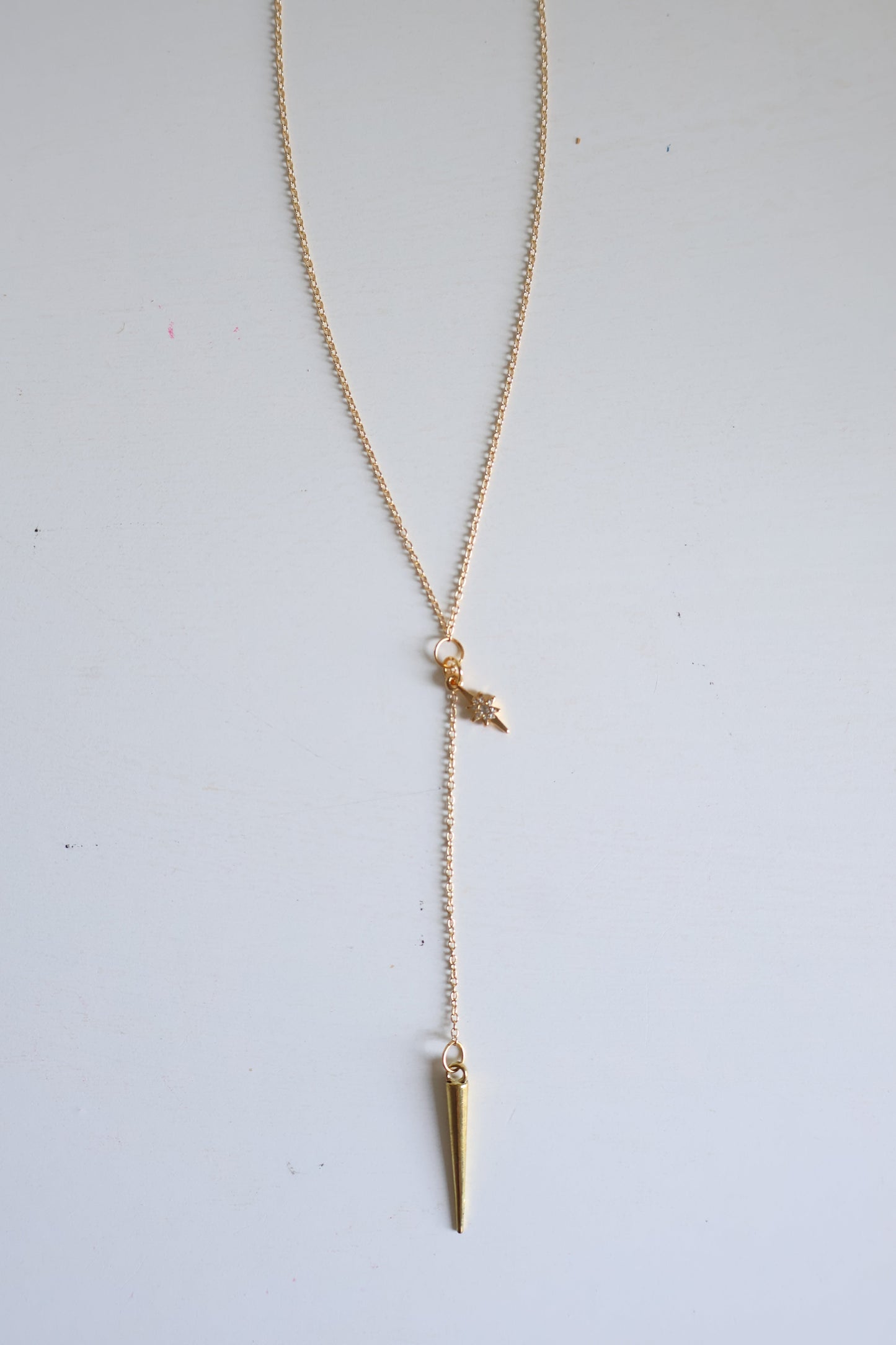 Gold necklace with a small pendant on a light gray background