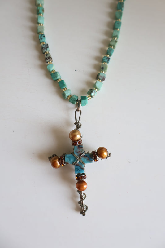 Beaded necklace with a cross pendant on a white background